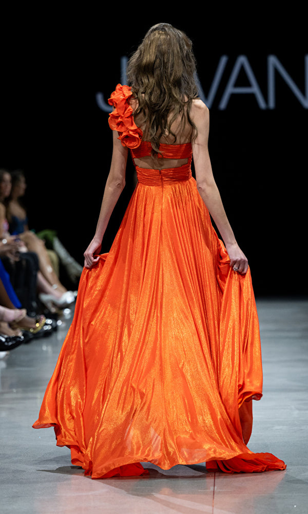 A model is seen from behind wearing the Jovani 37254 one-shoulder long metallic prom gown on the runway.